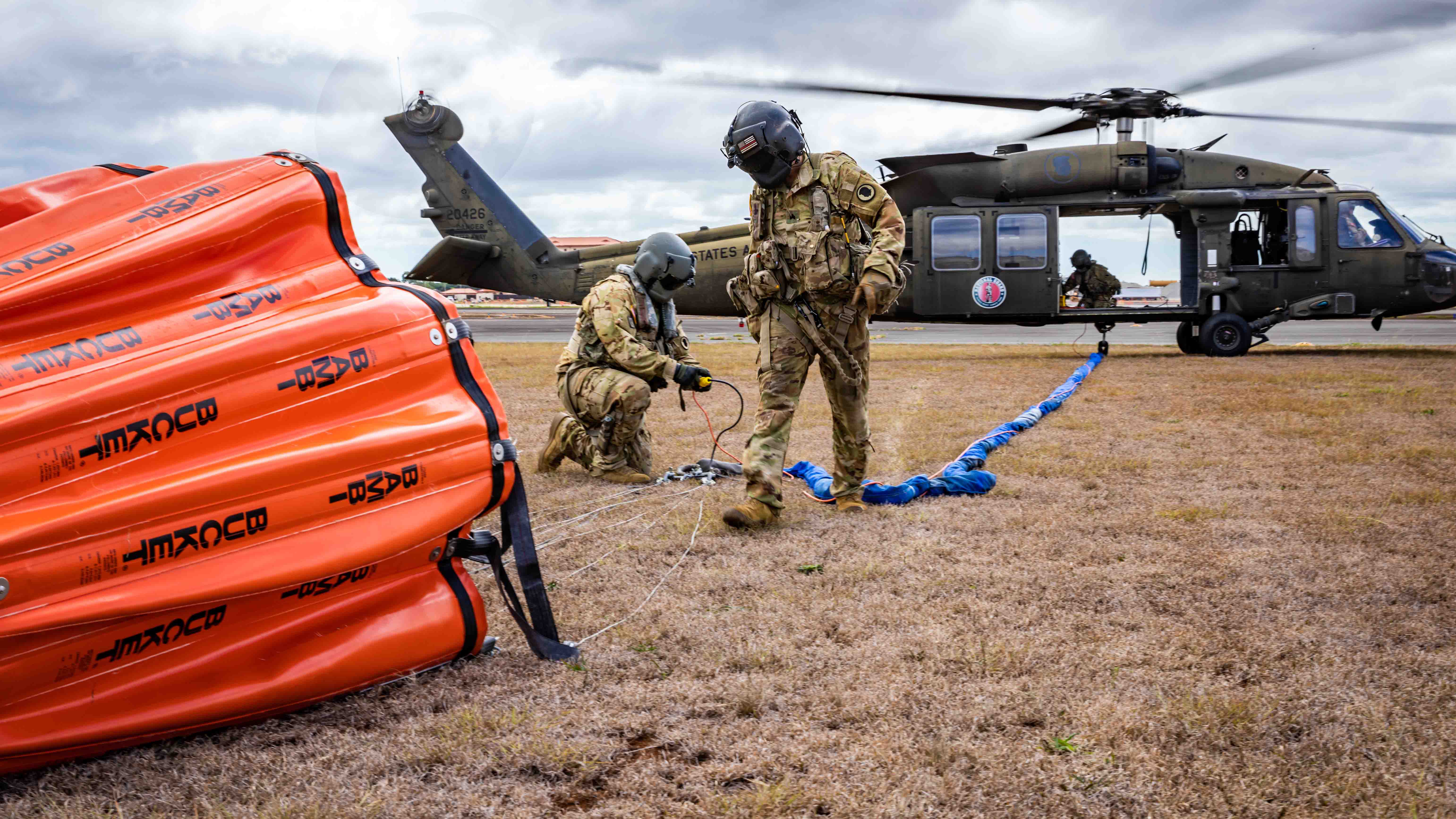 U.S. Soldiers assigned to the 1st Battalion, 183rd Aviation Regiment, the 1st Battalion, 189th Aviation Regiment and 3rd Battalion, 126th Aviation Regiment, Hawaii Army National Guard, secure a Bambi bucket to a UH-60M Black Hawk helicopter during aerial fire suppression water drop operations
