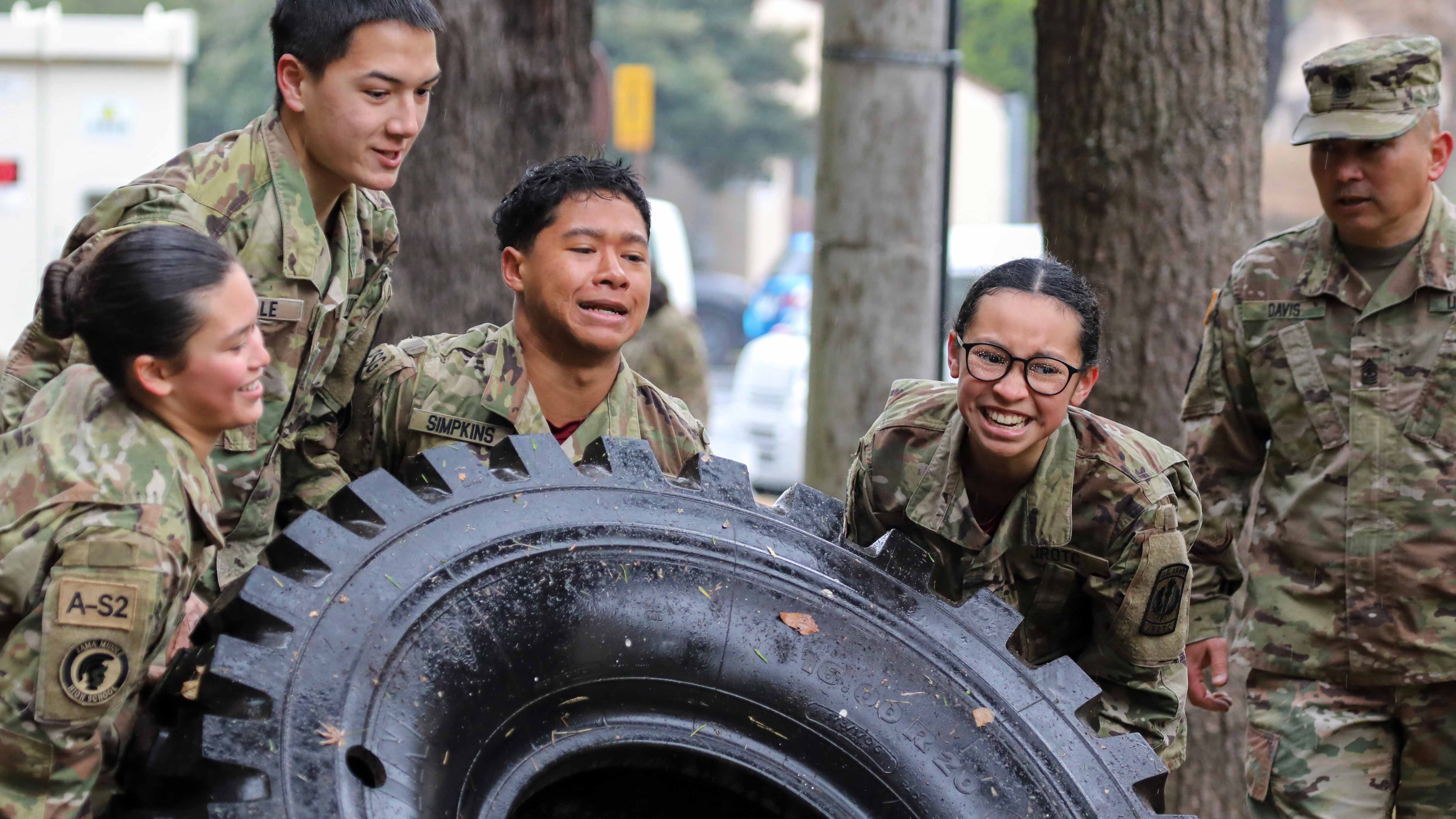 JROTC Cadets team up to flip over a tire as part of an obstacle course at Camp Zama