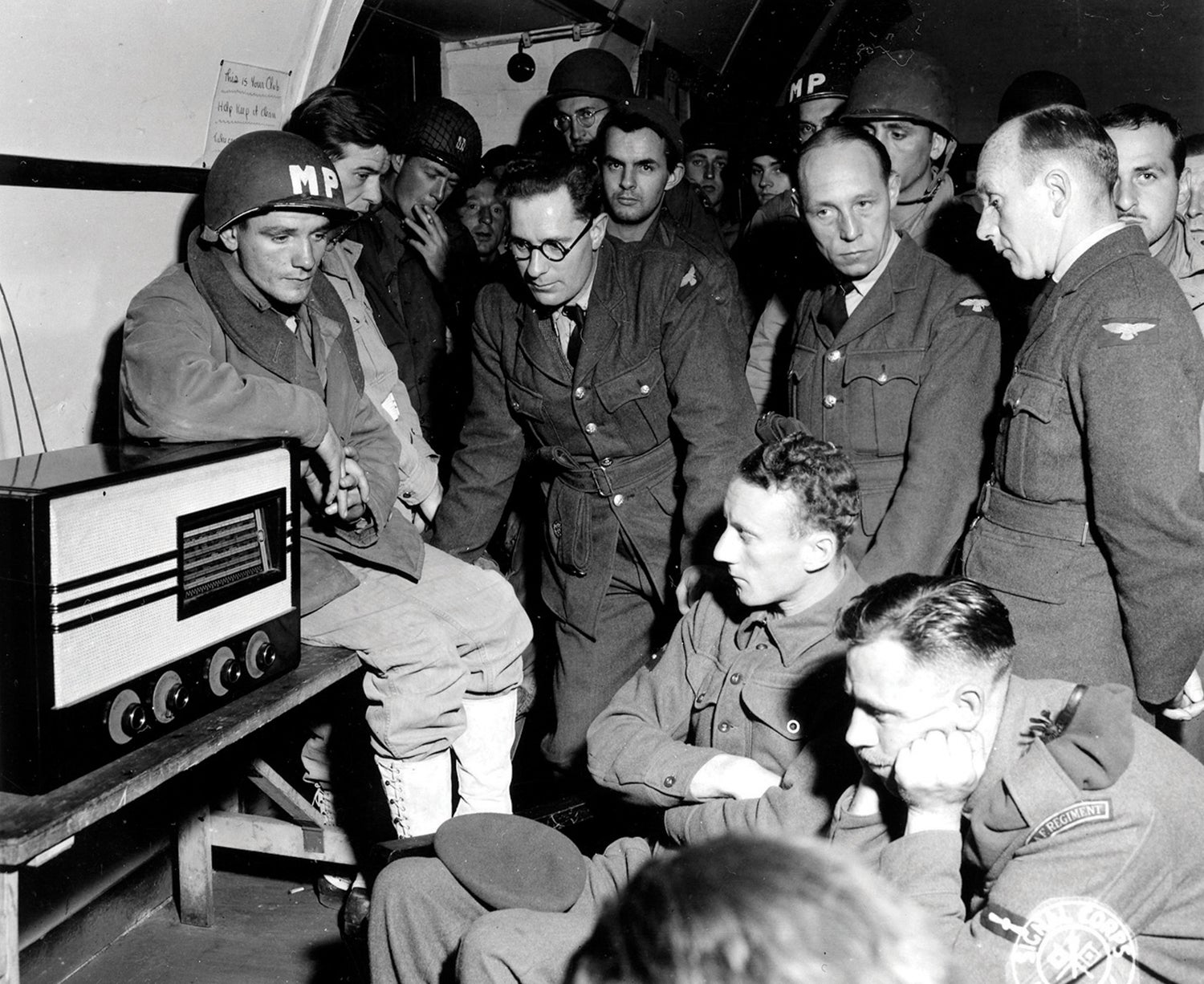 Troops listen to the radio on June 7, 1944, for news about progress on the Normandy beachhead. (Credit: National Archives/U.S. Army)
